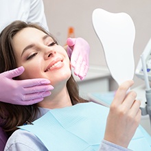 Woman in dental chair admiring the results of her cosmetic treatment