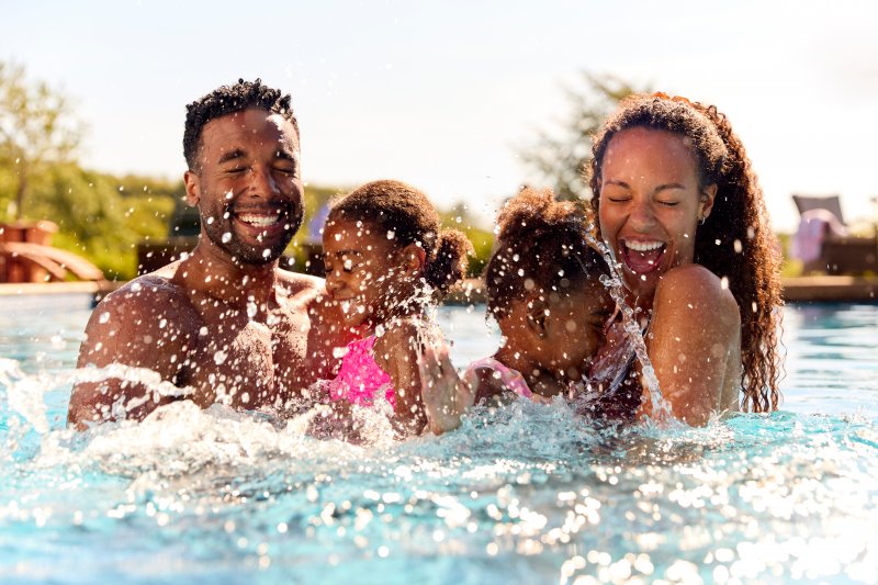 Family with good oral health swimming in a pool