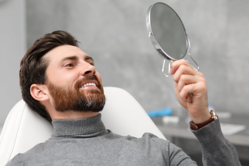 a patient checking his smile with a mirror