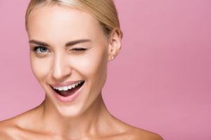 Woman smiling and winking on pink background